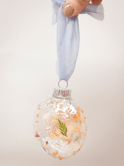 Real pressed flowers resined onto a plastic ball ornament.